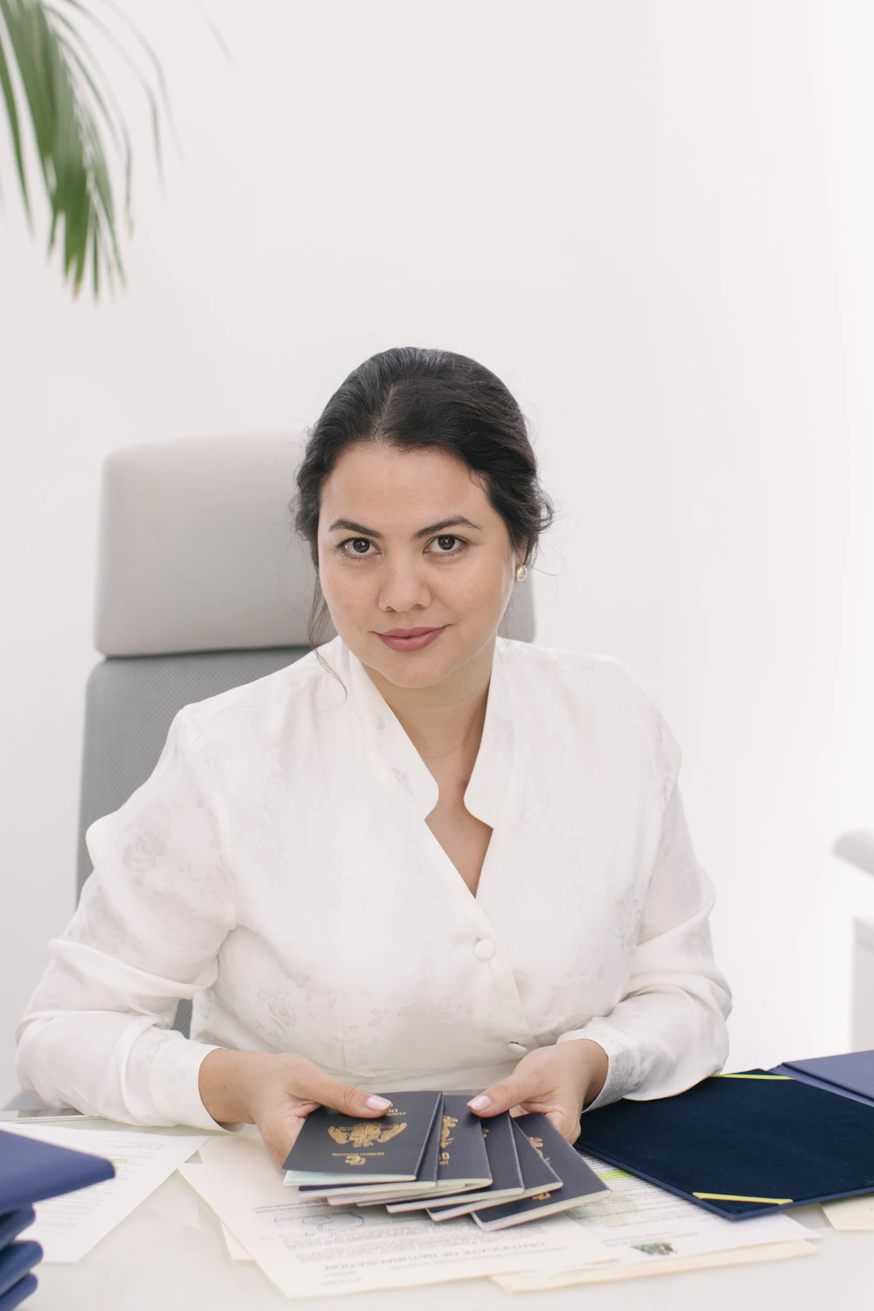 Giselle Bru, Founder of PassPro, photographed at her desk with the Caribbean passports and Naturalization Certificates that represent the firm's daily work.